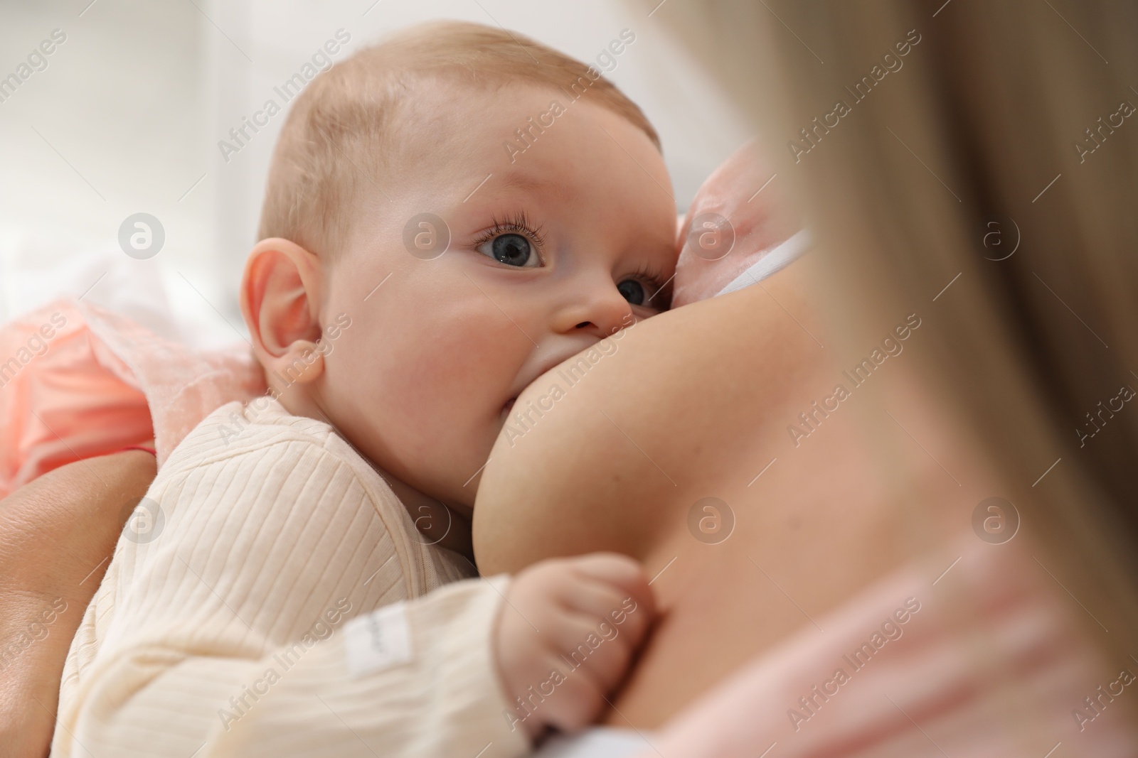 Photo of Mother breastfeeding her little baby indoors, closeup