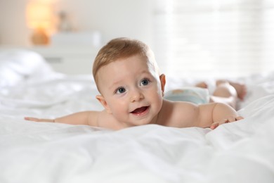 Cute little baby in diaper on bed at home