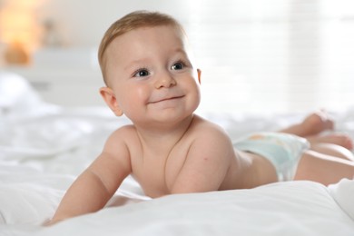 Cute little baby in diaper on bed at home