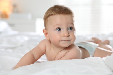 Cute little baby in diaper on bed at home