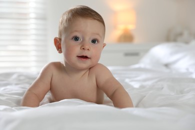 Photo of Cute little baby on bed at home, space for text