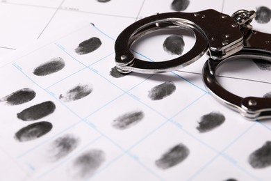 Photo of Human fingerprints and handcuffs on paper, closeup. Criminal conviction