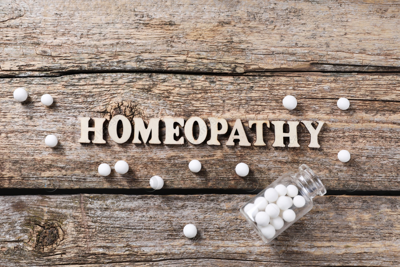 Photo of Word Homeopathy and pills on wooden background, flat lay