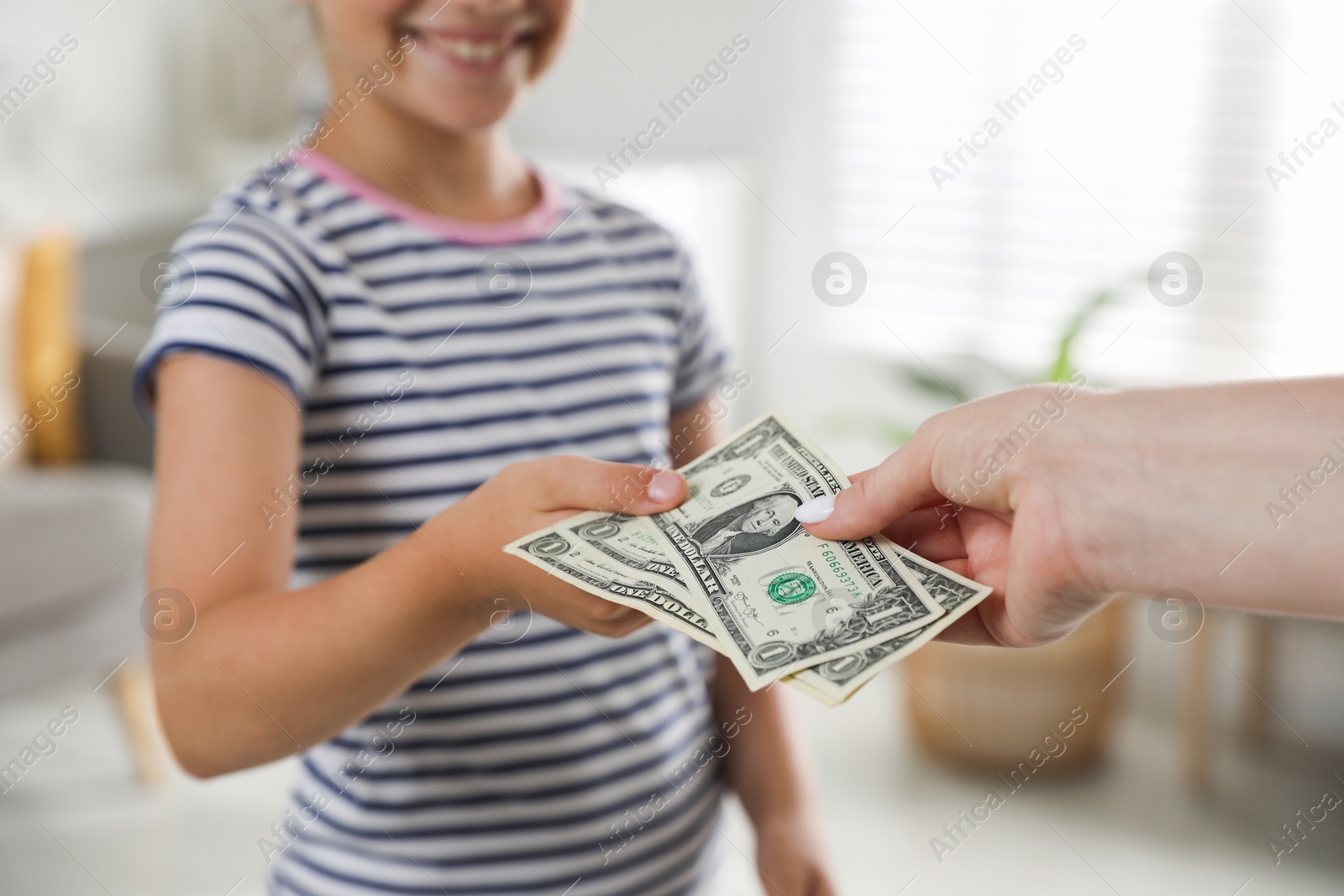 Photo of Mother giving pocket money to her daughter at home, closeup