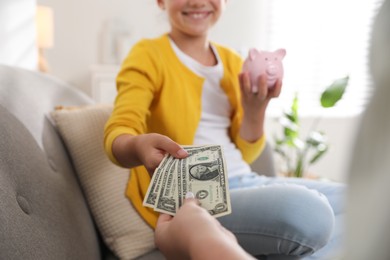 Mother giving pocket money to her daughter at home, closeup