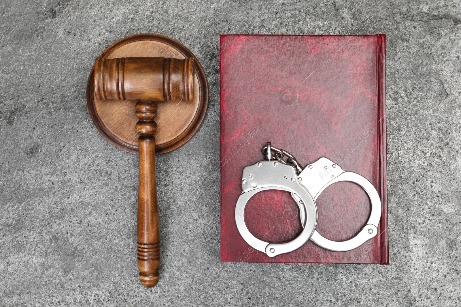 Photo of Book, judge's gavel and handcuffs on gray textured table, flat lay