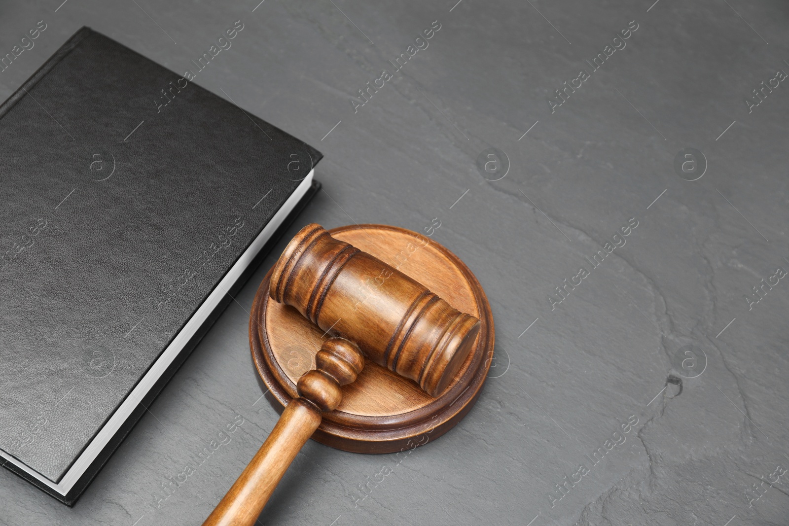 Photo of Book and judge's gavel on gray textured table. Space for text