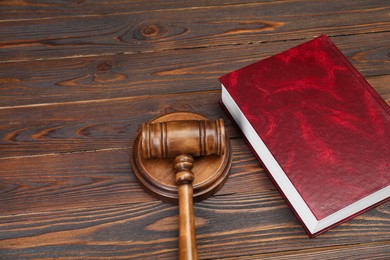 Book and judge's gavel on wooden table, space for text