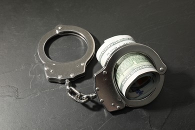 Photo of Handcuffs with dollar banknotes on grey textured table