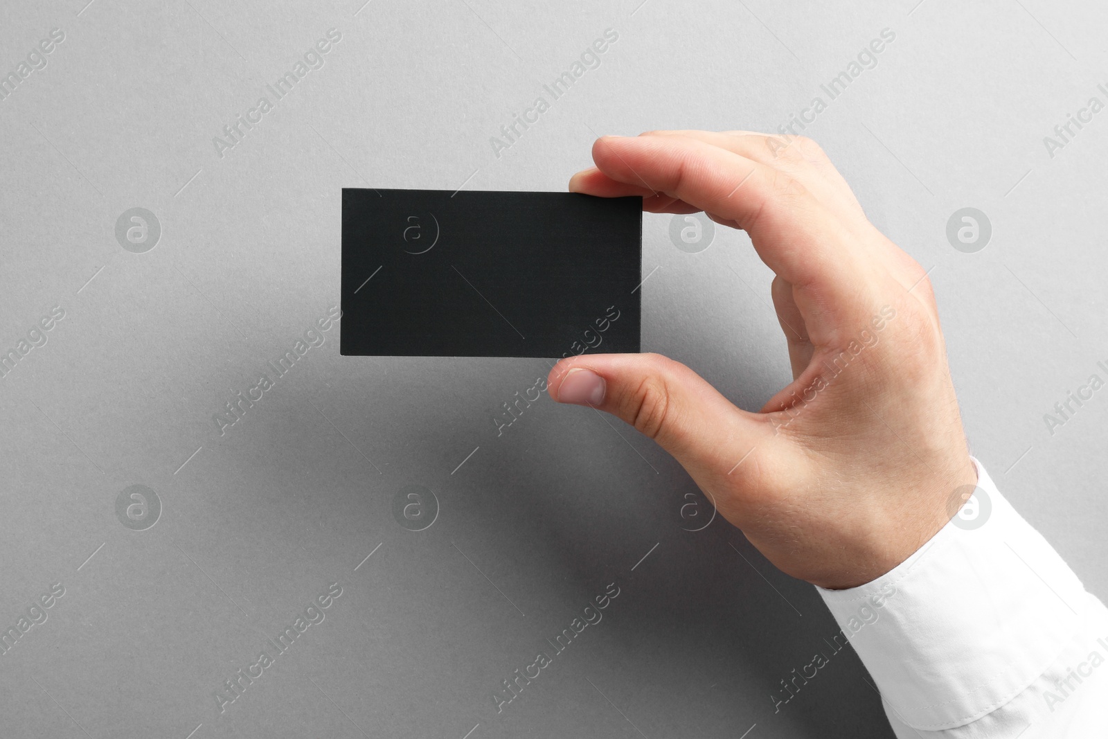 Photo of Woman with blank business card on grey background, closeup. Mockup for design