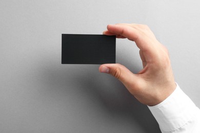 Woman with blank business card on grey background, closeup. Mockup for design