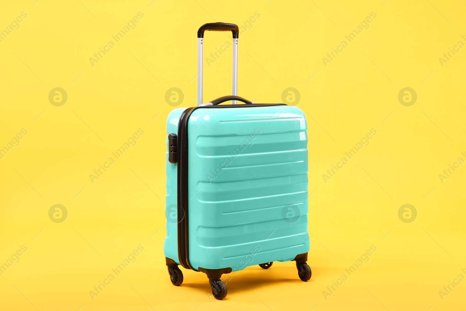 Photo of One new turquoise suitcase on yellow background