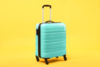 Photo of One new turquoise suitcase on yellow background