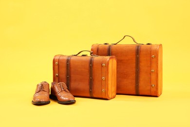 Photo of Suitcases and leather shoes on yellow background