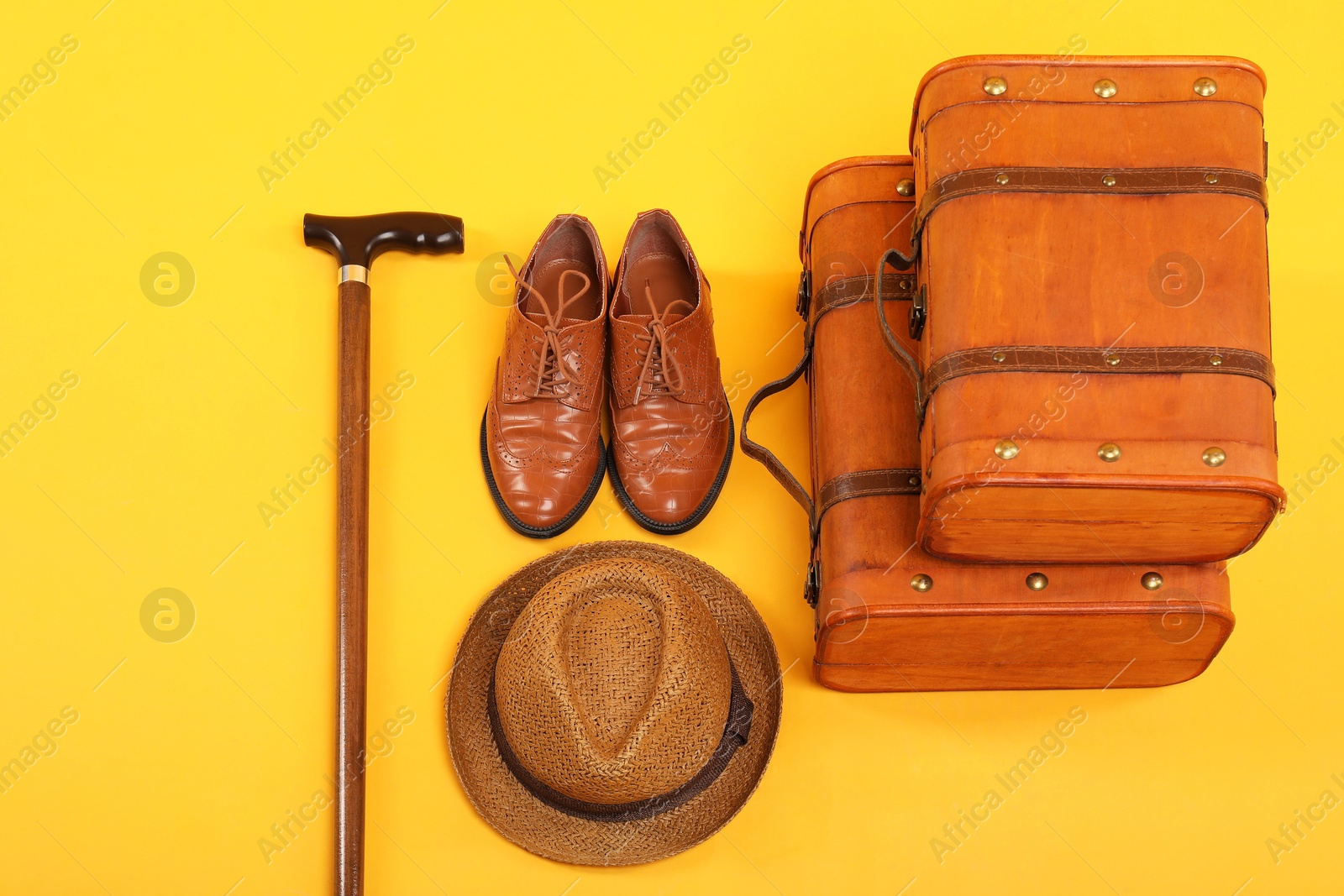 Photo of Suitcases, shoes, hat and cane on yellow background, above view