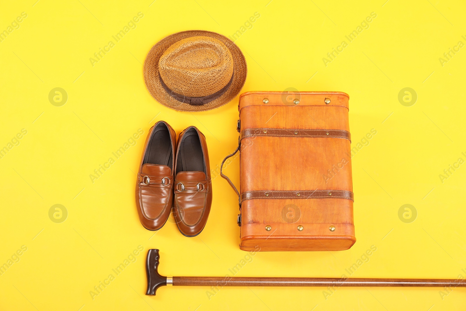 Photo of Suitcase, shoes, hat and cane on yellow background, flat lay