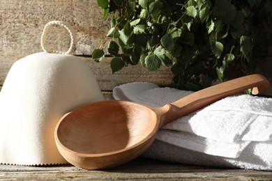 Photo of Sauna equipment. Felt wool hat, ladle and towel on wooden surface, closeup