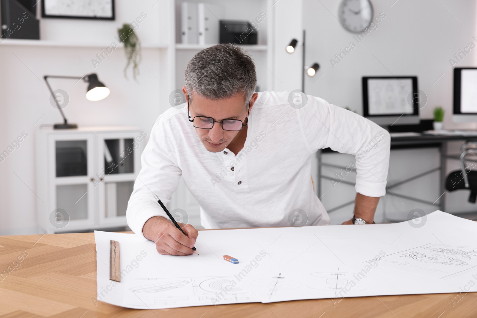 Photo of Architect making engineering drawing at wooden table in office