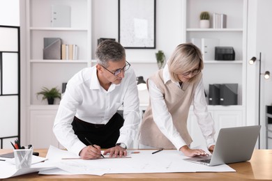 Architects making engineering drawing at wooden table in office