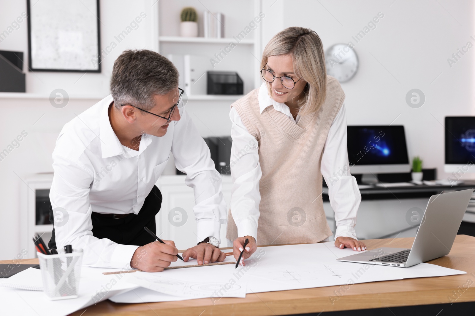 Photo of Architects making engineering drawing at wooden table in office