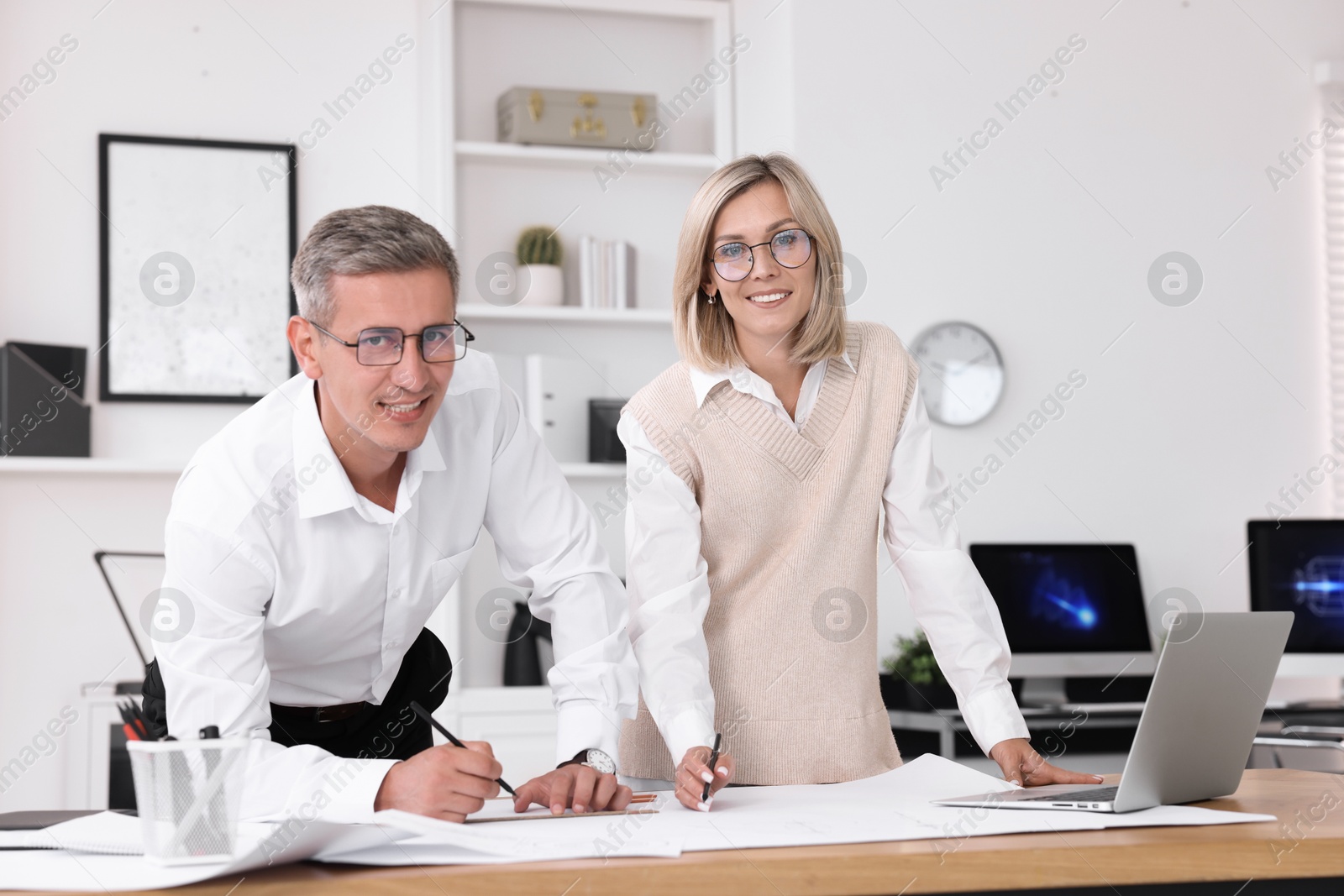 Photo of Architects making engineering drawing at wooden table in office