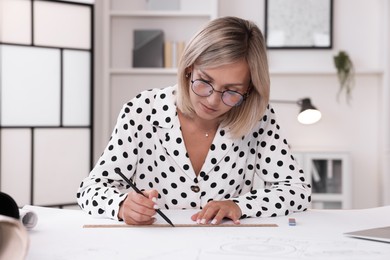 Architect making engineering drawing at table in office