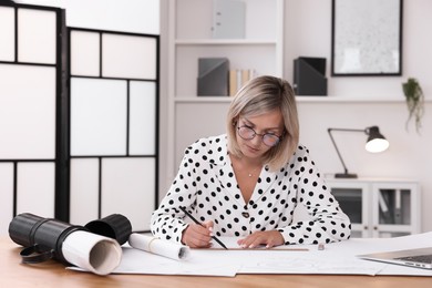 Architect making engineering drawing at table in office