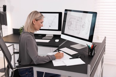 Architect making engineering drawing at table in office