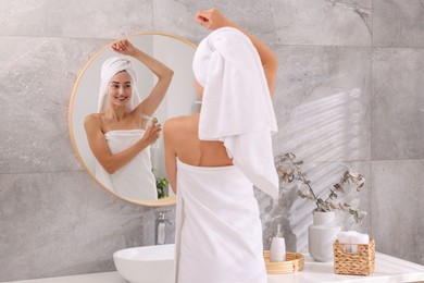 Photo of Smiling woman applying spray deodorant near mirror at home, back view