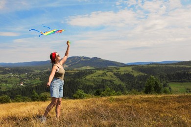 Smiling woman flying kite at field under blue sky. Space for text