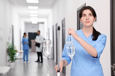 Nurse with IV drip in hospital hallway, selective focus