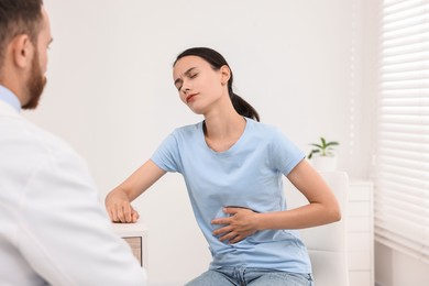 Photo of Doctor consulting patient with stomach pain in clinic