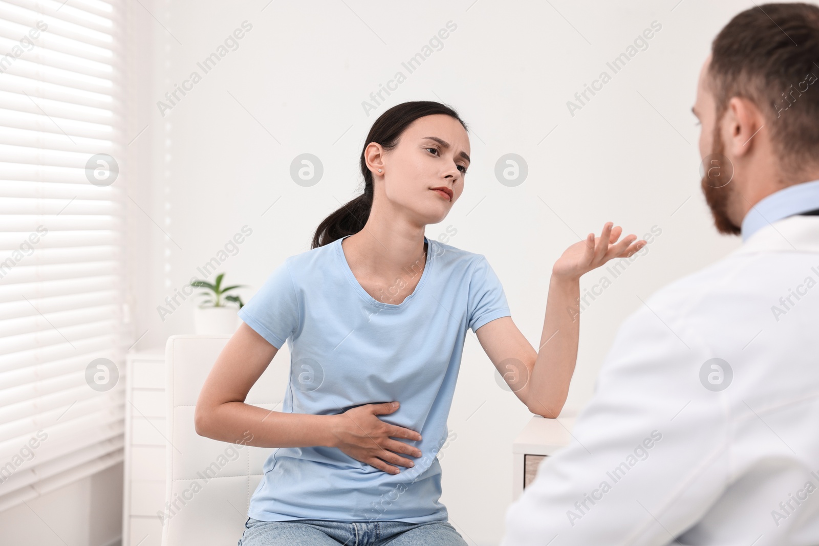 Photo of Doctor consulting patient with stomach pain in clinic