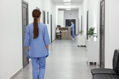 Photo of Nurse in uniform walking in hospital hallway, back view