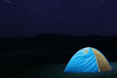 Photo of Modern camping tent in wilderness at night, slow shutter speed effect