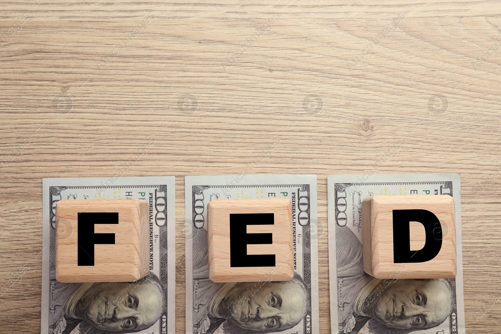 Photo of Cubes with letters Fed (Federal Reserve System) and dollar banknotes on wooden table, flat lay. Space for text