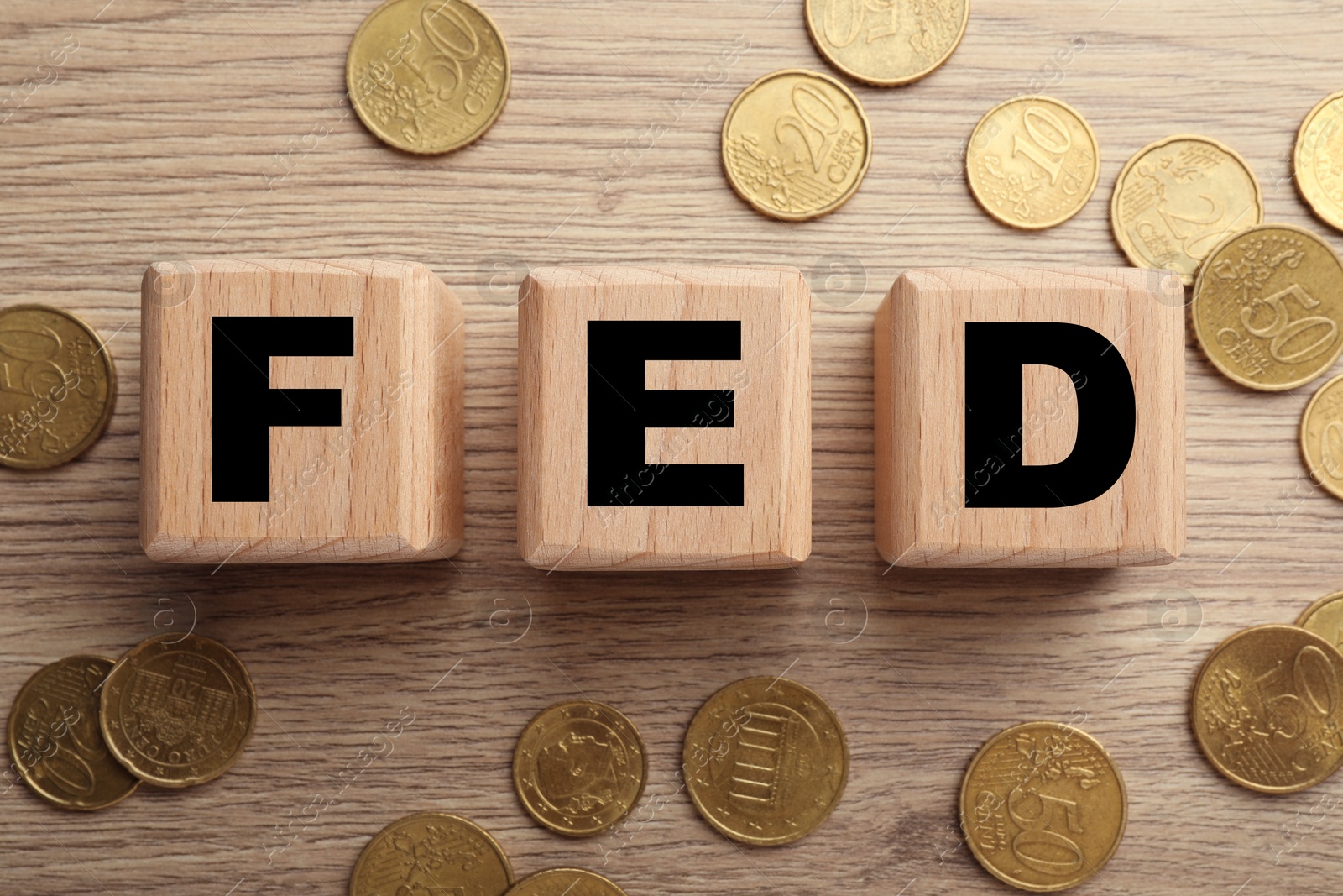 Photo of Cubes with letters Fed (Federal Reserve System) and coins on wooden table, flat lay