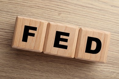 Photo of Cubes with letters Fed (Federal Reserve System) on wooden table, top view