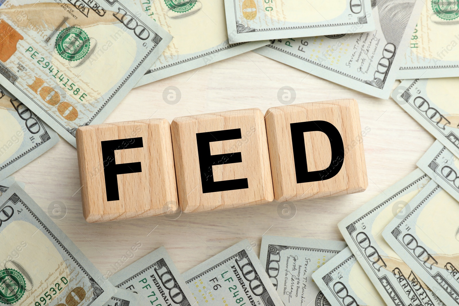 Photo of Cubes with letters Fed (Federal Reserve System) and dollar banknotes on white wooden table, flat lay