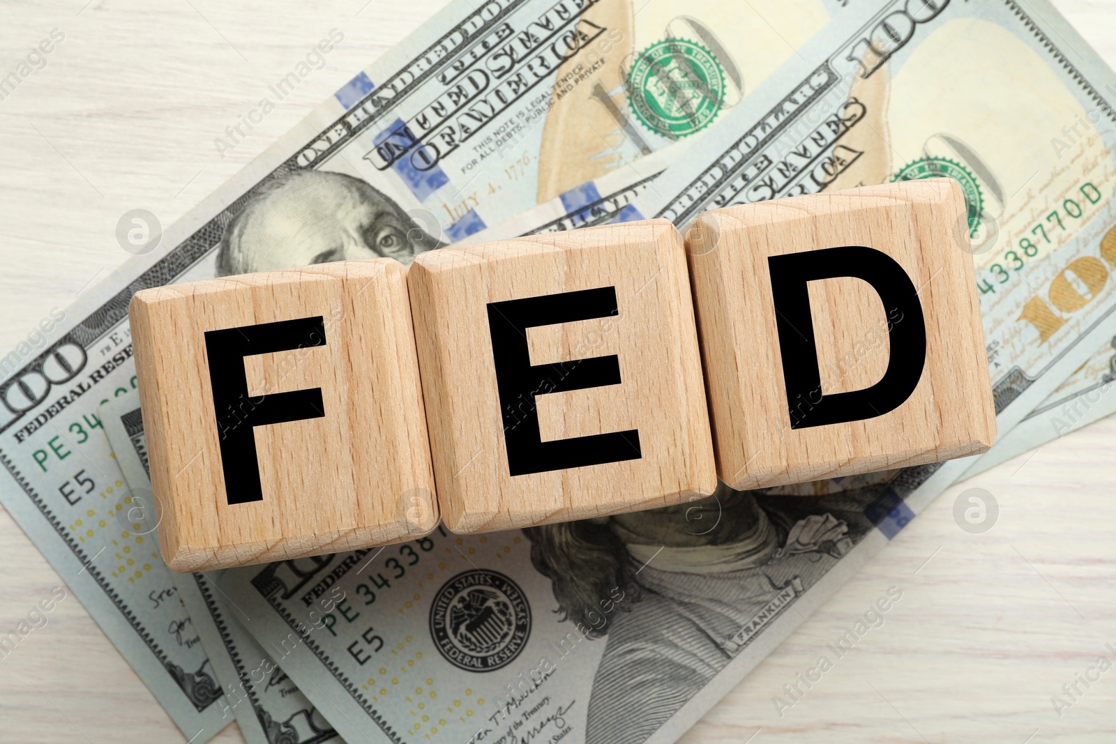 Photo of Cubes with letters Fed (Federal Reserve System) and dollar banknotes on white wooden table, flat lay