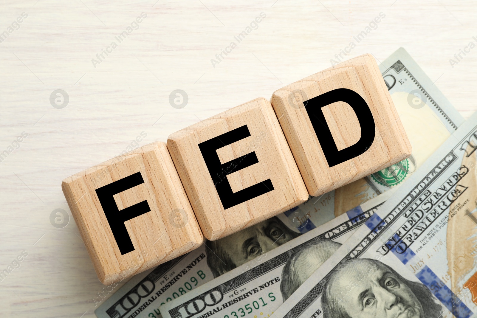 Photo of Cubes with letters Fed (Federal Reserve System) and dollar banknotes on white wooden table, flat lay