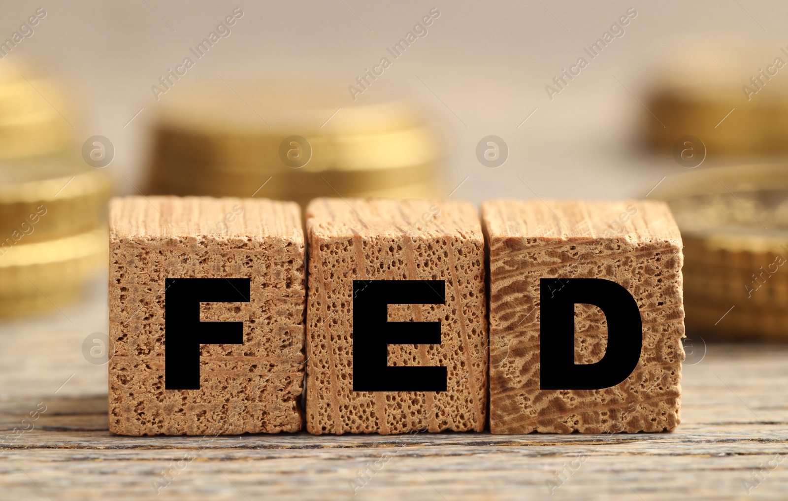 Photo of Cubes with letters Fed (Federal Reserve System) and coins on wooden table, closeup