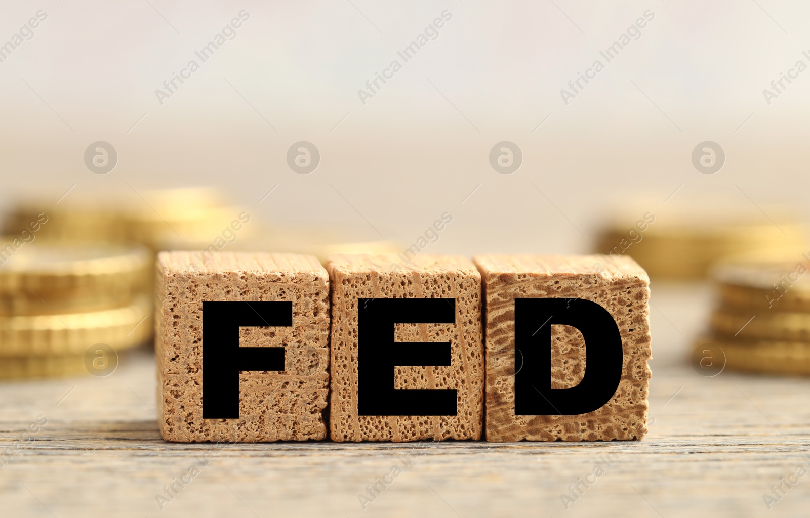 Photo of Cubes with letters Fed (Federal Reserve System) and coins on wooden table, closeup