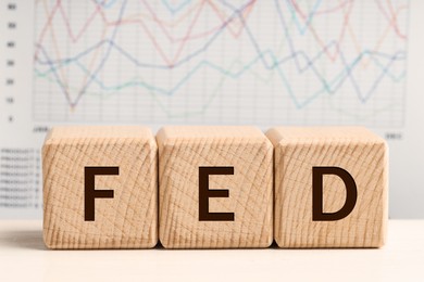 Photo of Cubes with letters Fed (Federal Reserve System) on wooden table, closeup