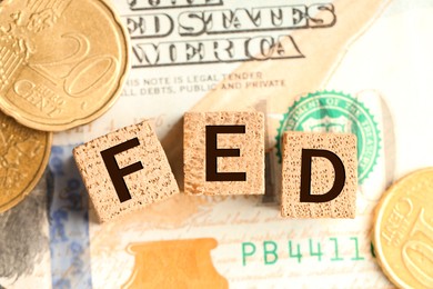 Photo of Wooden cubes with letters Fed (Federal Reserve System), dollar banknotes and coins, flat lay