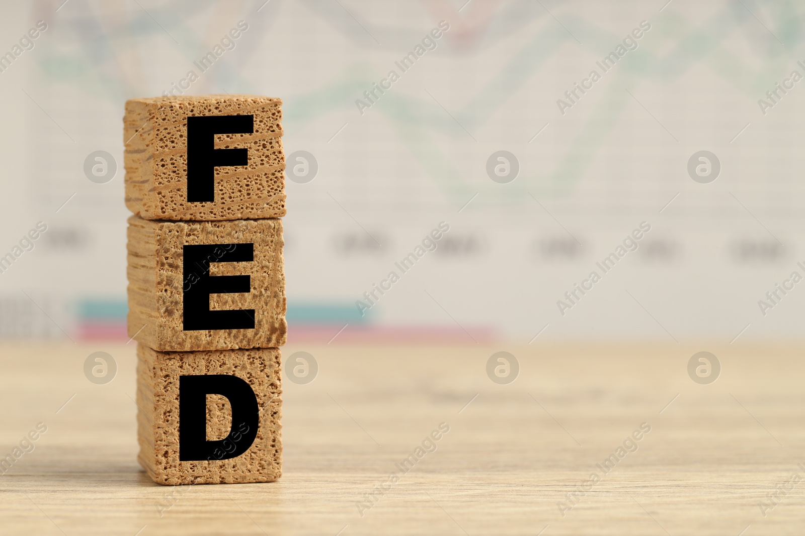 Photo of Cubes with letters Fed (Federal Reserve System) on wooden table, closeup. Space for text