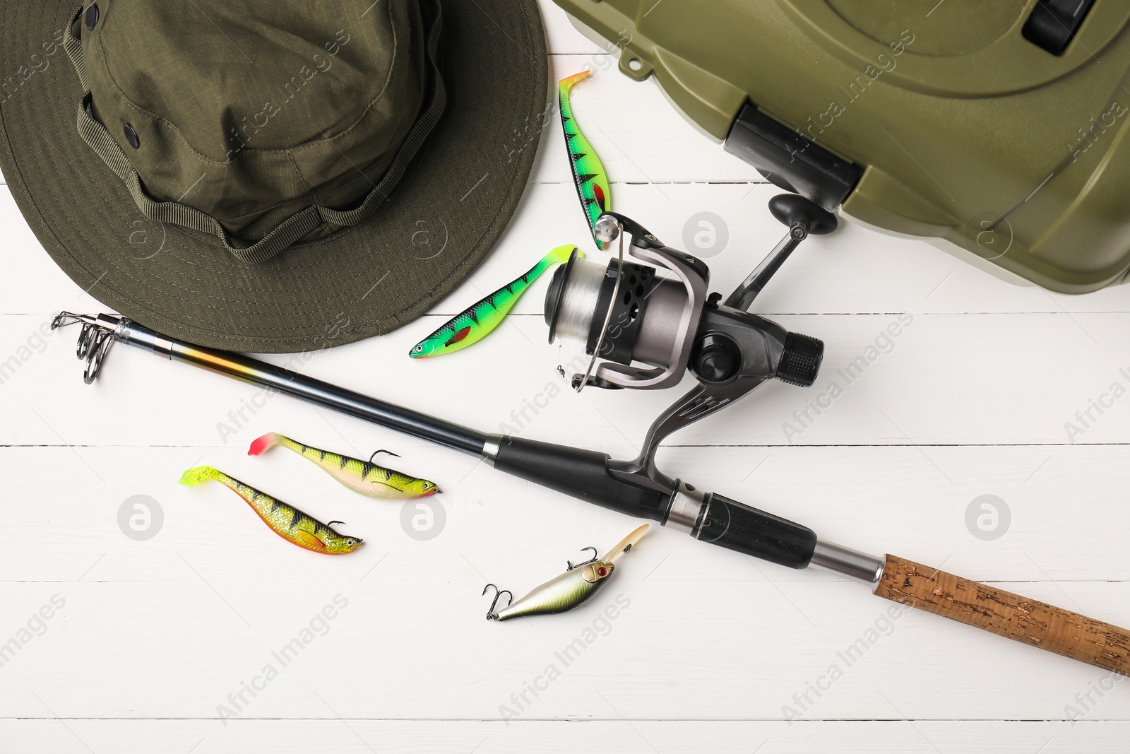 Photo of Fishing rod with spinning reel, hat, baits and tackle box on white wooden table, flat lay