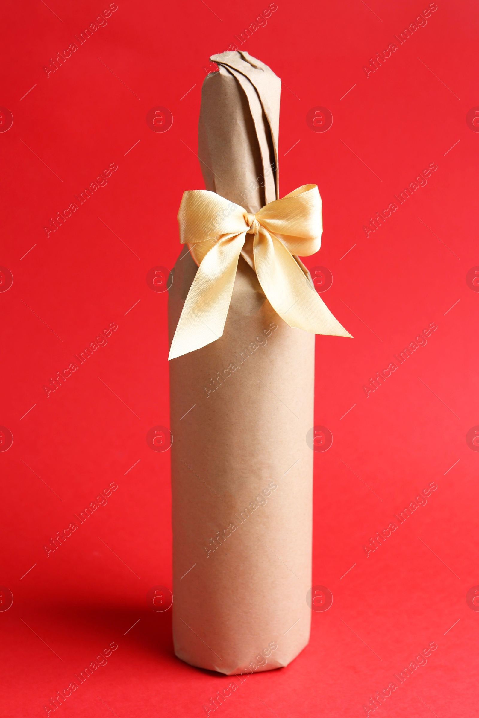 Photo of Wine packed bottle with ribbon on red background