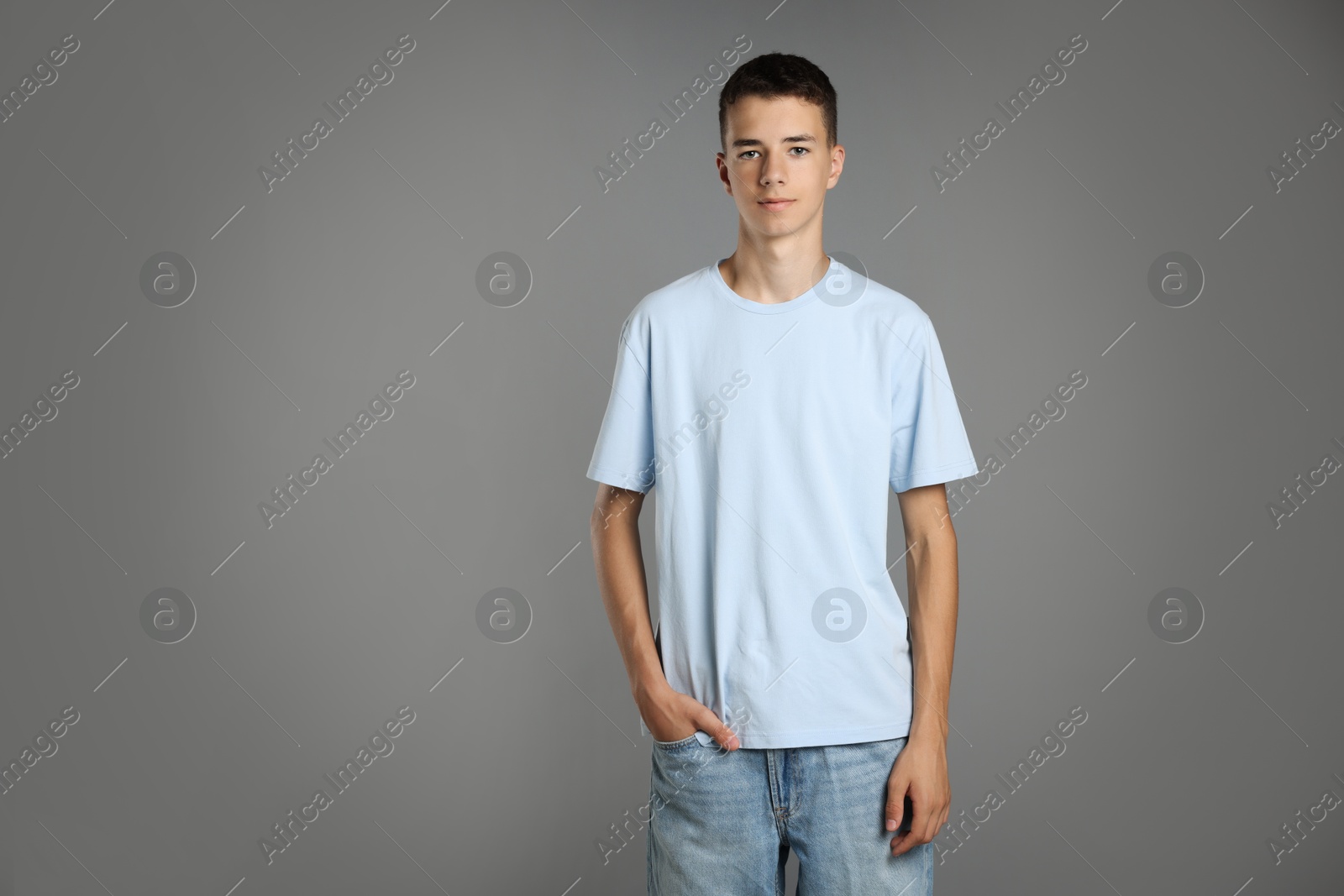 Photo of Teenage boy wearing light blue t-shirt on grey background, space for text