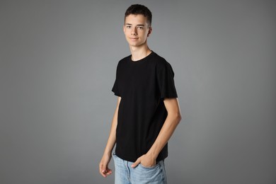 Teenage boy wearing black t-shirt on grey background